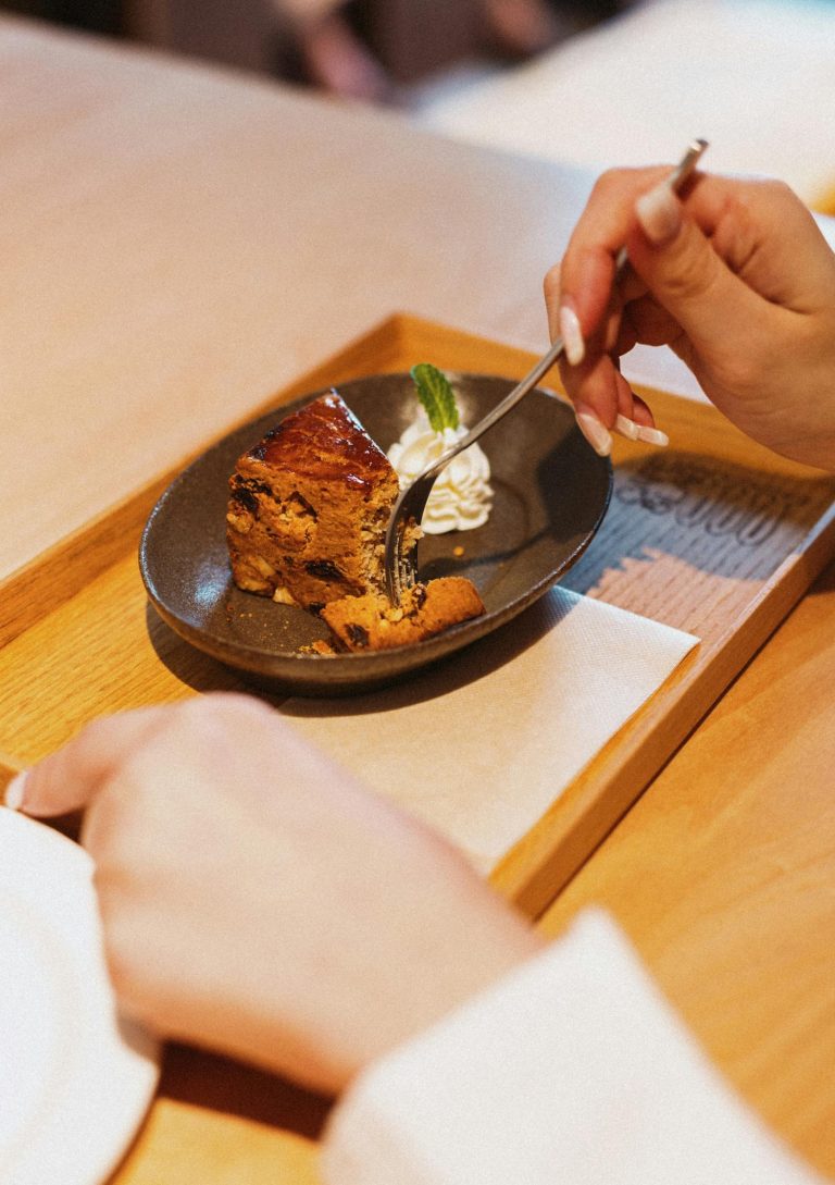 Close-up of a person enjoying a dessert served on a wooden tray, highlighting elegant presentation.